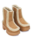 Pair of tan boots with white fur lining on a white background