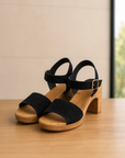 Black sandals with wooden sole on a wooden surface