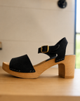 Black clog sandal with wooden sole on a light surface