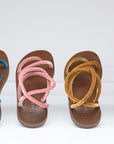 Five pairs of sandals with colorful straps on a white background