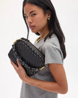 Woman holding a black woven handbag against a white background