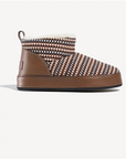A single slip-on ankle boot with a brown leather side panel and sole, a brown, beige, and black woven patterned upper, and a white faux-fur lining, shown against a light gray background.