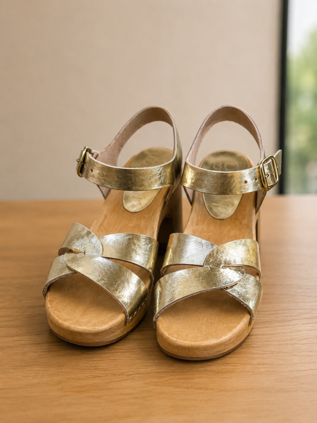Gold sandals with wooden soles on a wooden surface