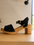 Black clog sandal with wooden sole on a light surface