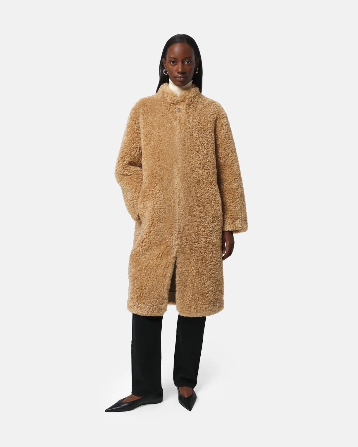 Person wearing a beige teddy coat on a white background