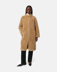 Person wearing a beige teddy coat on a white background