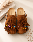 Pair of brown fringed shoes with colorful beads on a light background