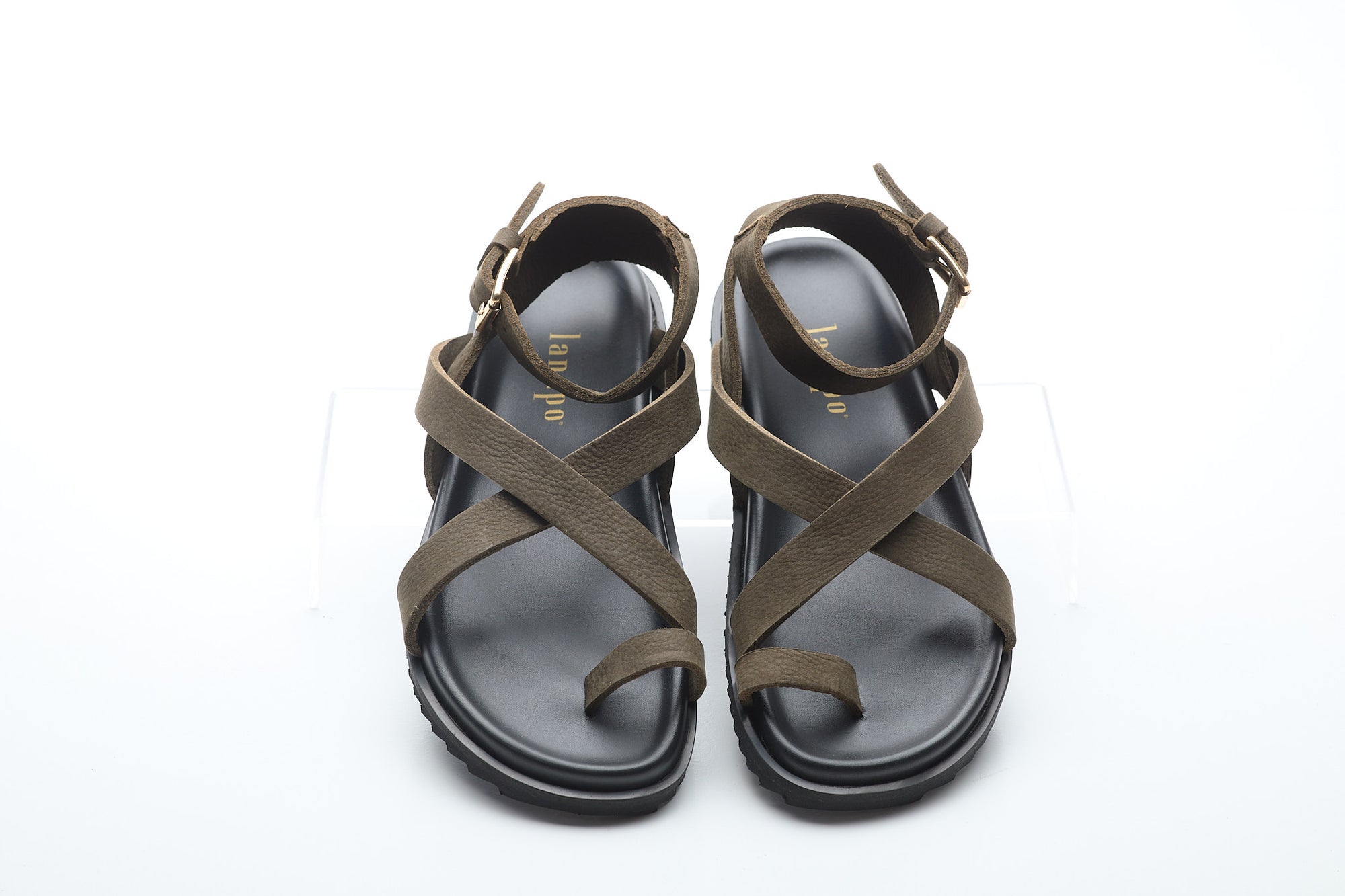 Pair of green sandals with criss-cross straps on a white background