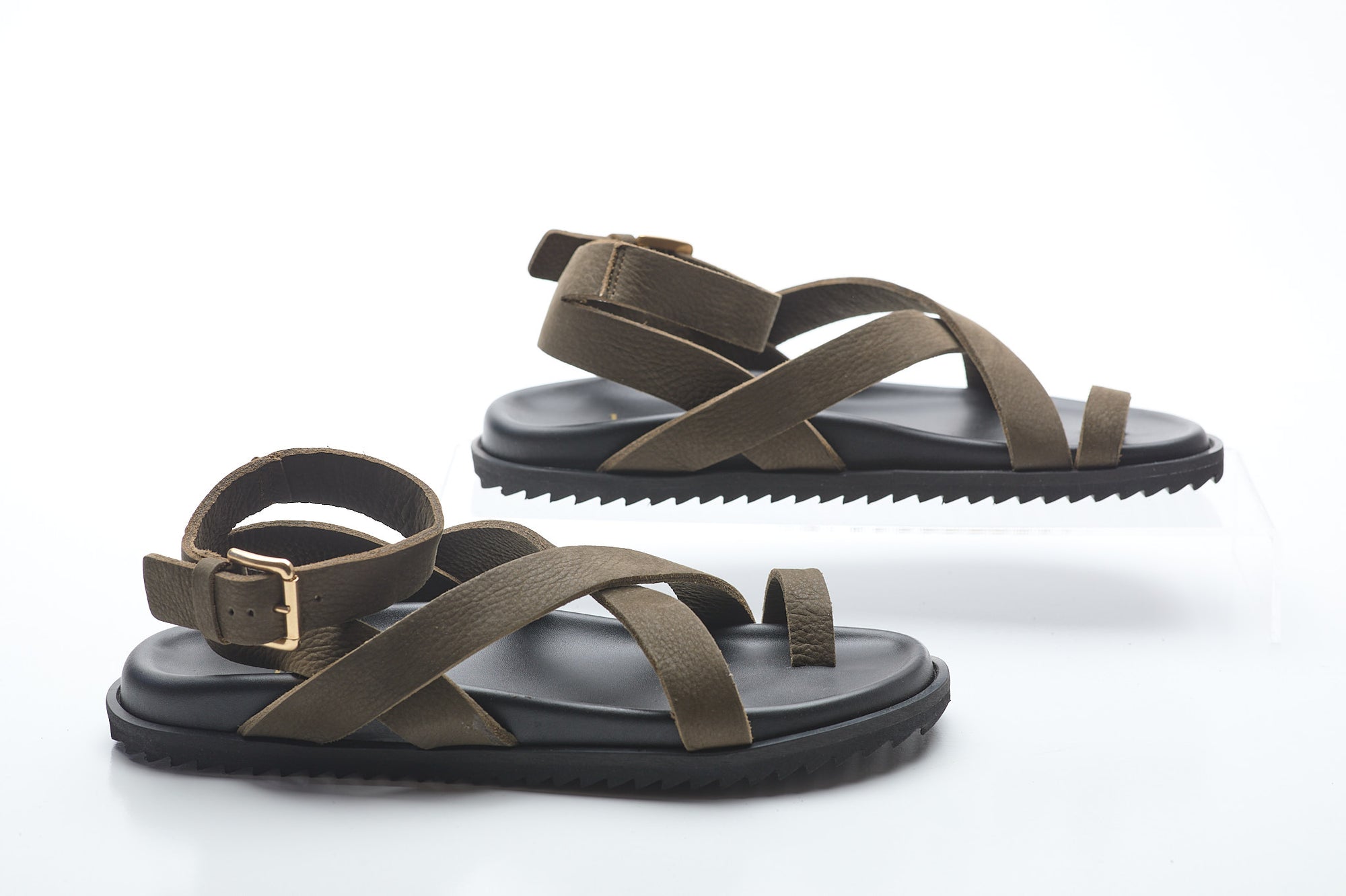 Pair of sandals with brown straps and black soles on a white background