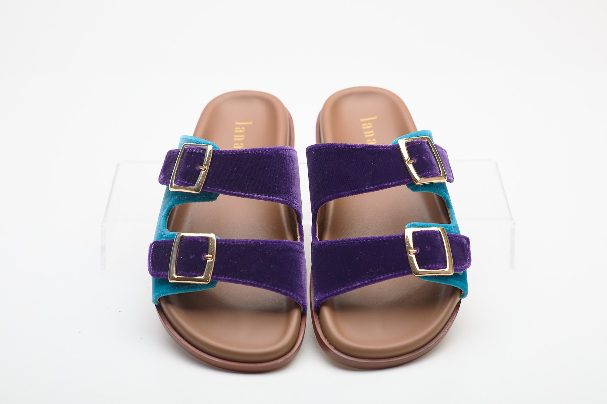 Pair of purple sandals with gold buckles on a white background