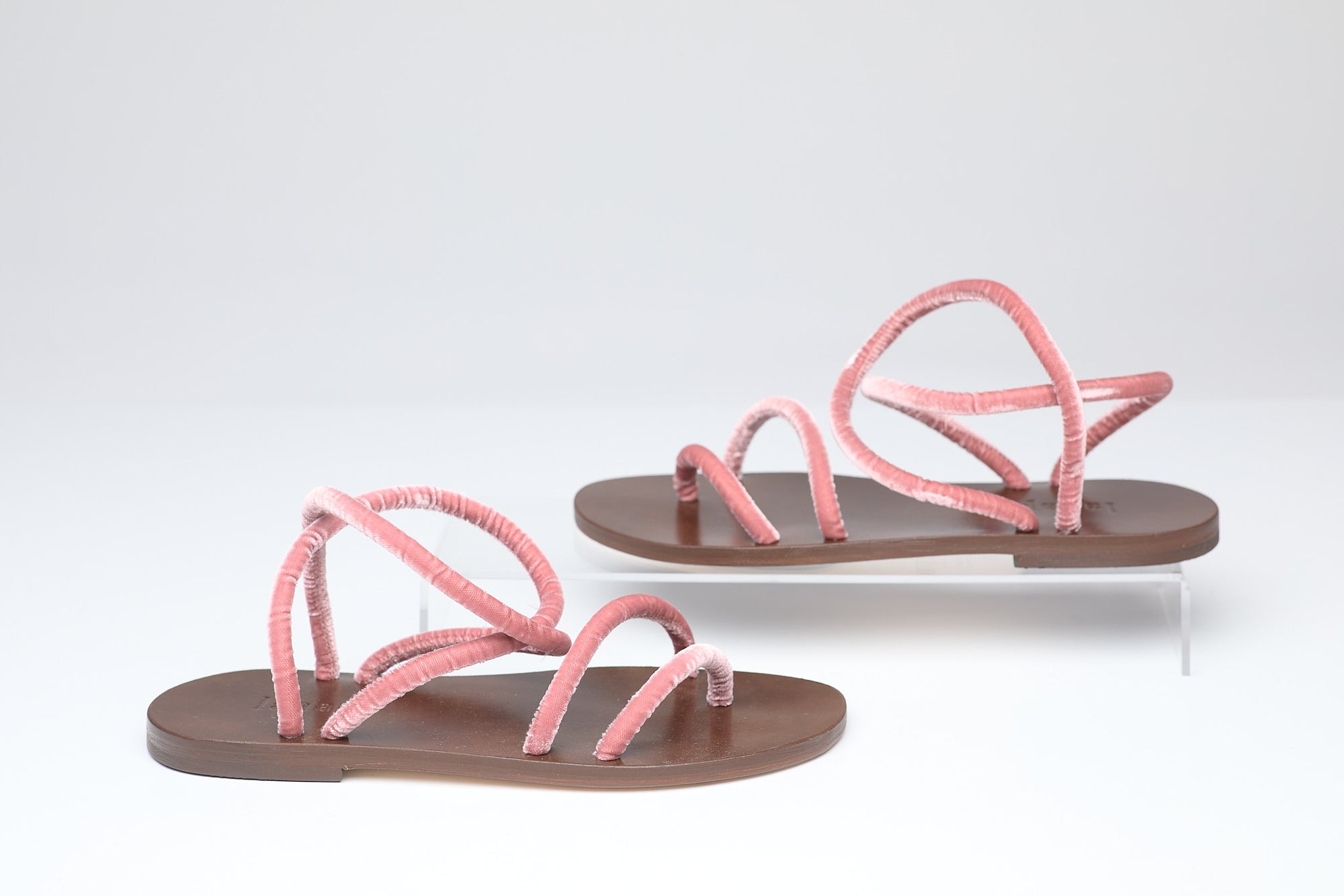 Pair of pink sandals with brown soles on a white background