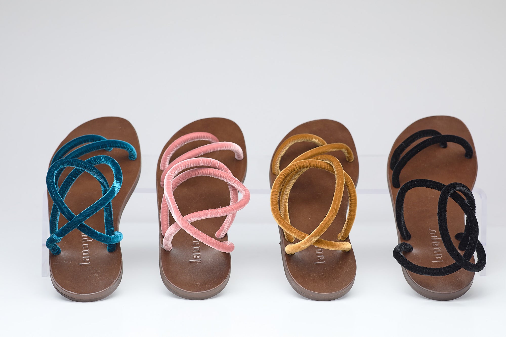 Five pairs of sandals with colorful straps on a white background