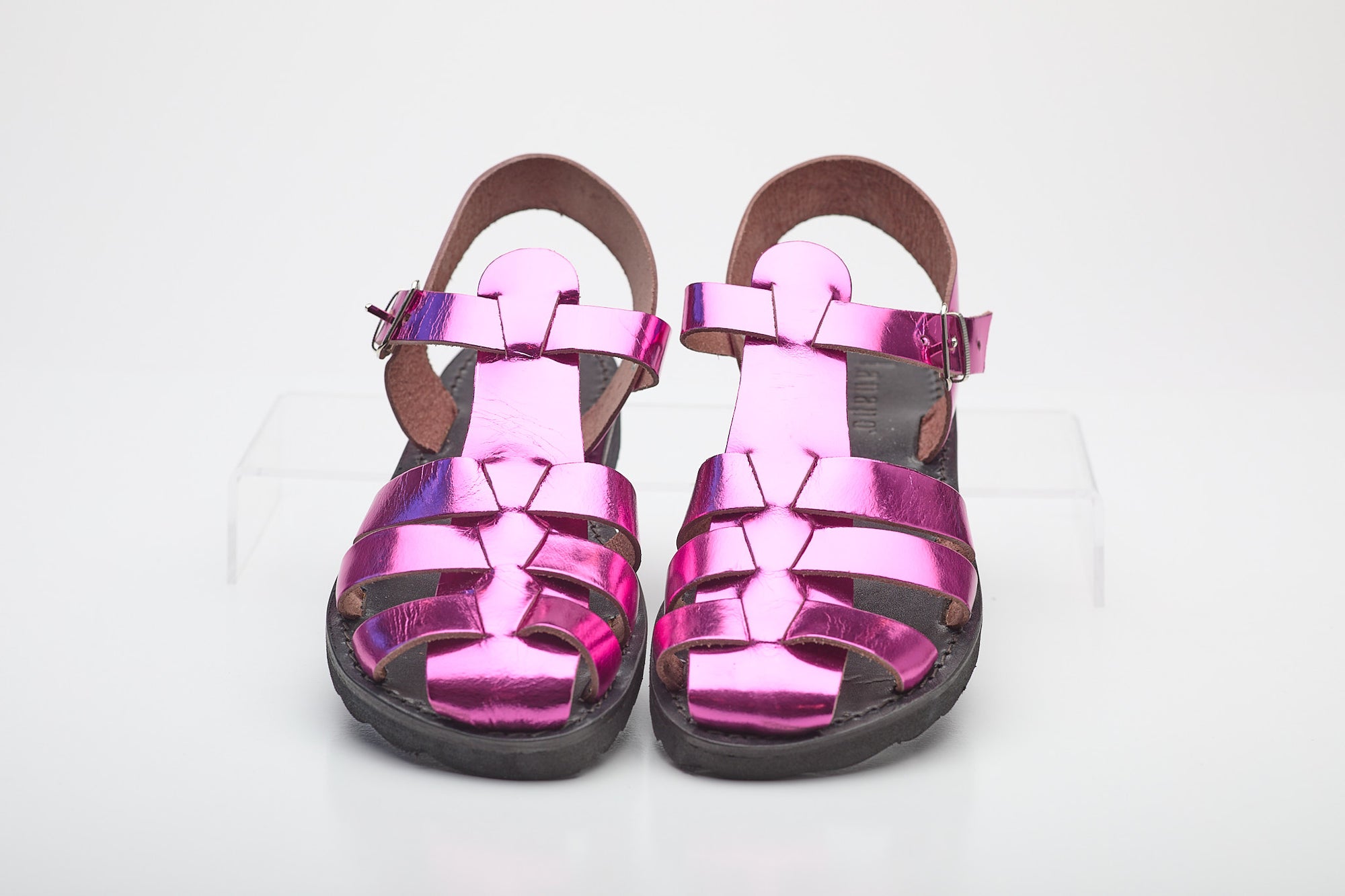 Pair of pink metallic sandals on a white background