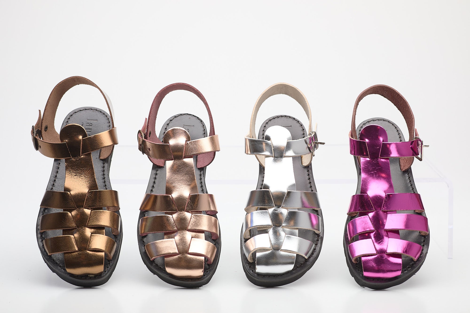 Four pairs of metallic sandals in different colors on a white background