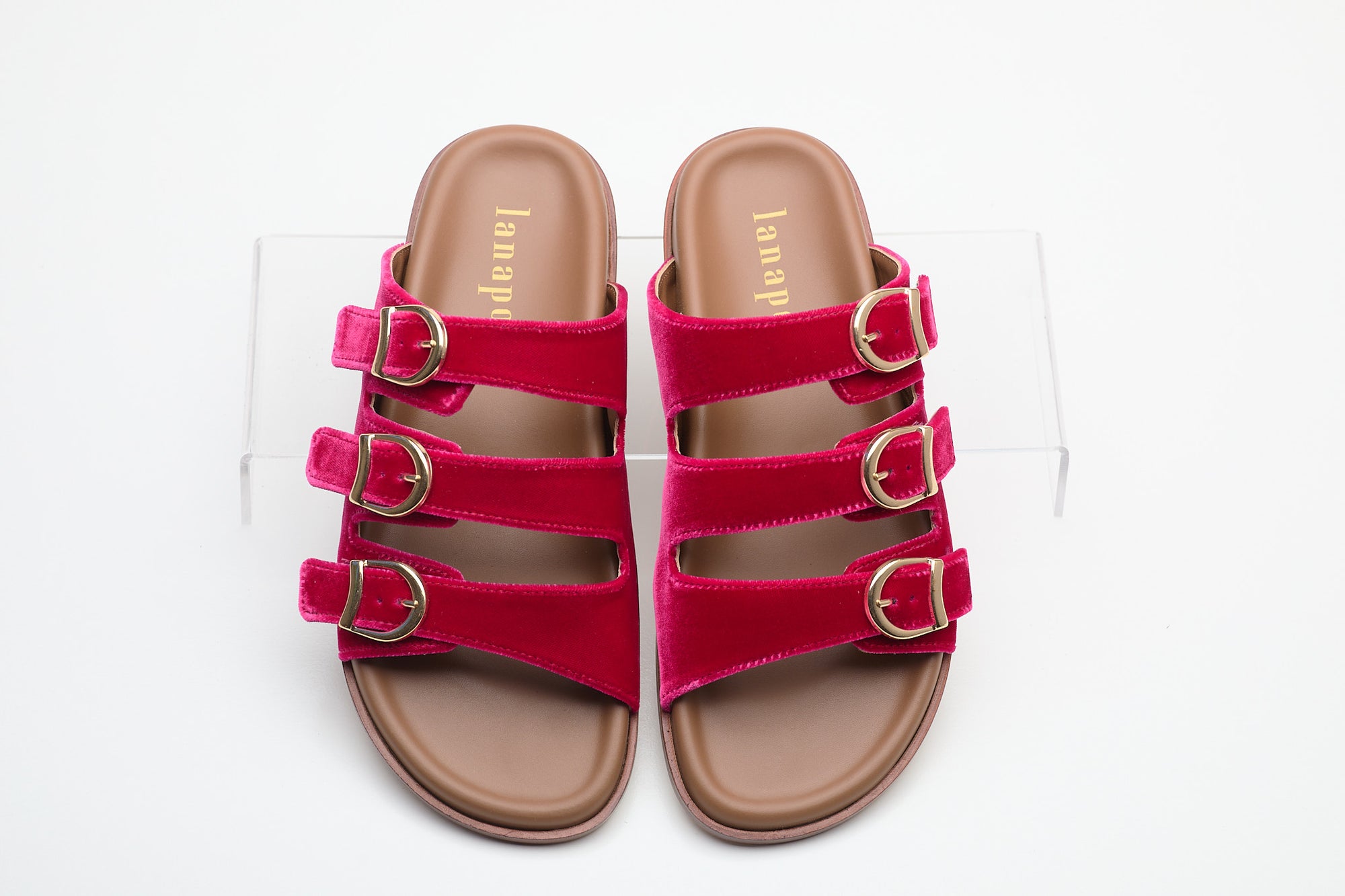 Pair of pink sandals with brown soles on a white background
