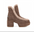 A single brown suede ankle boot with a chunky block heel, platform sole, and beige braided trim along the collar and vamp, shown in profile against a white background.