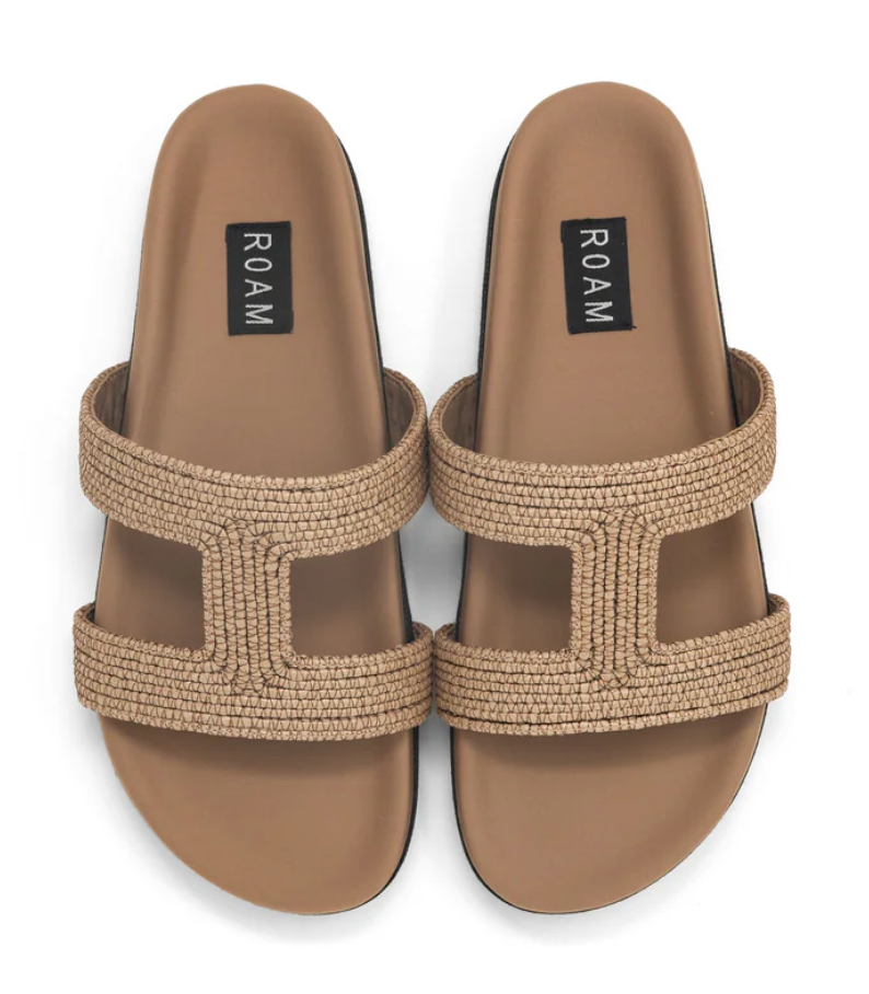 A pair of ROAM raffia cuff sandals in natural color with cutout straps and a flat sole.