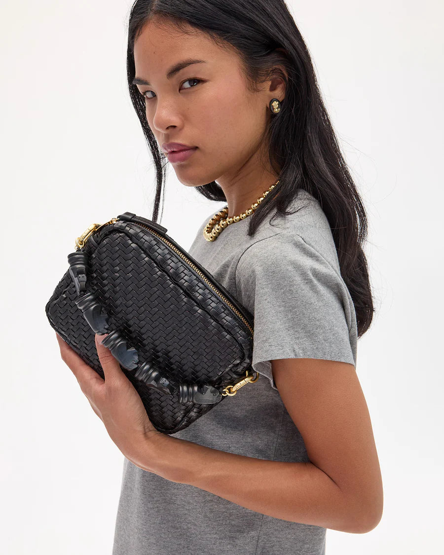 Woman holding a black woven handbag against a white background